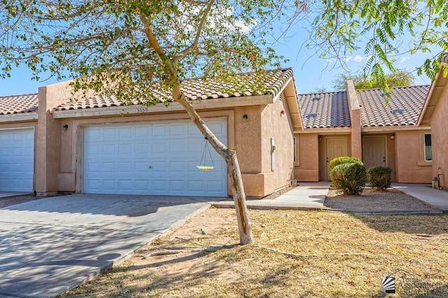 townhome / multi-family property with stucco siding, a tiled roof, concrete driveway, and a garage