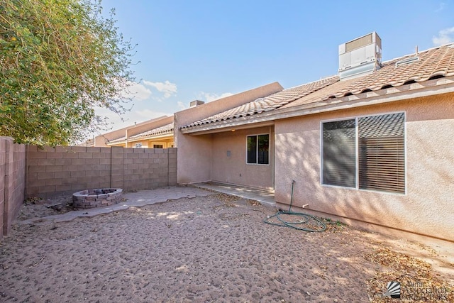 back of house with stucco siding, a fire pit, a tile roof, and fence