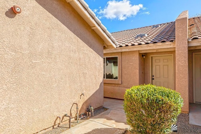 entrance to property with stucco siding and a tiled roof