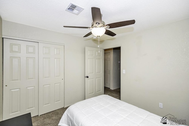 carpeted bedroom featuring a closet, visible vents, a textured ceiling, and a ceiling fan