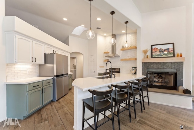 kitchen with sink, kitchen peninsula, stainless steel refrigerator, and a breakfast bar