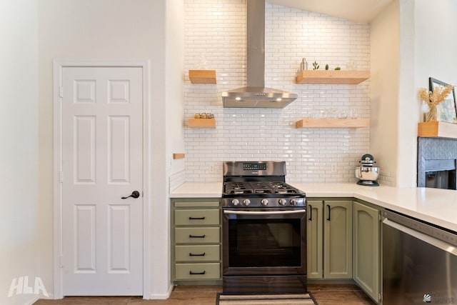 kitchen featuring wall chimney exhaust hood, vaulted ceiling, appliances with stainless steel finishes, green cabinets, and backsplash