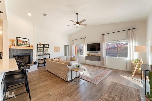 living room with lofted ceiling, a fireplace, light hardwood / wood-style floors, and ceiling fan