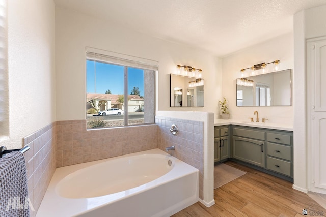 bathroom with a washtub, vanity, wood-type flooring, and a textured ceiling