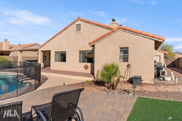 back of property with a fenced in pool and a patio area