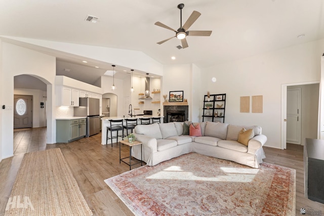 living room featuring high vaulted ceiling, light hardwood / wood-style floors, sink, and ceiling fan