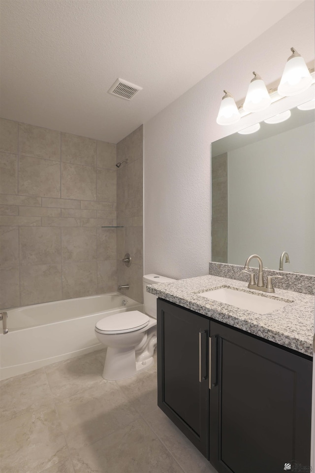 full bathroom with toilet, tiled shower / bath, vanity, and a textured ceiling