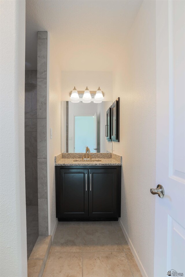 bathroom featuring vanity, tile patterned floors, and tiled shower