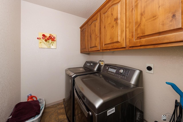 clothes washing area with washer and dryer, cabinets, and a textured ceiling