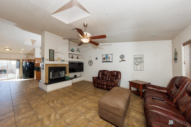 living room with vaulted ceiling with skylight, ceiling fan, and a textured ceiling