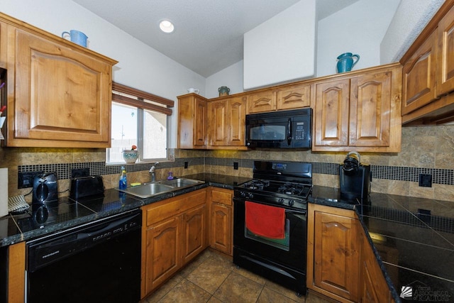 kitchen with sink, tasteful backsplash, dark tile patterned floors, vaulted ceiling, and black appliances