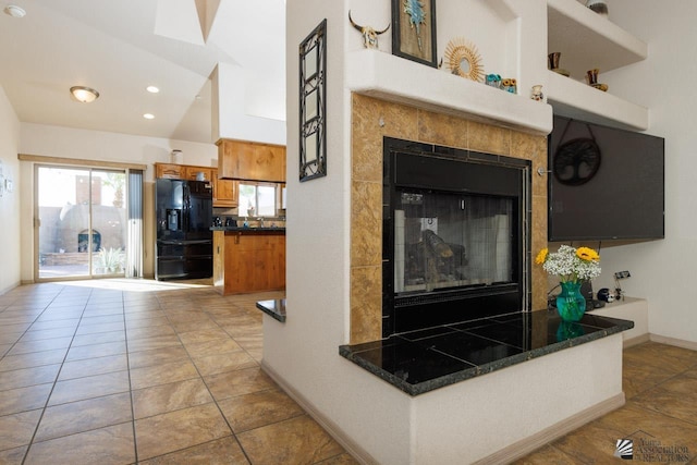 kitchen with lofted ceiling, black fridge with ice dispenser, and light tile patterned floors