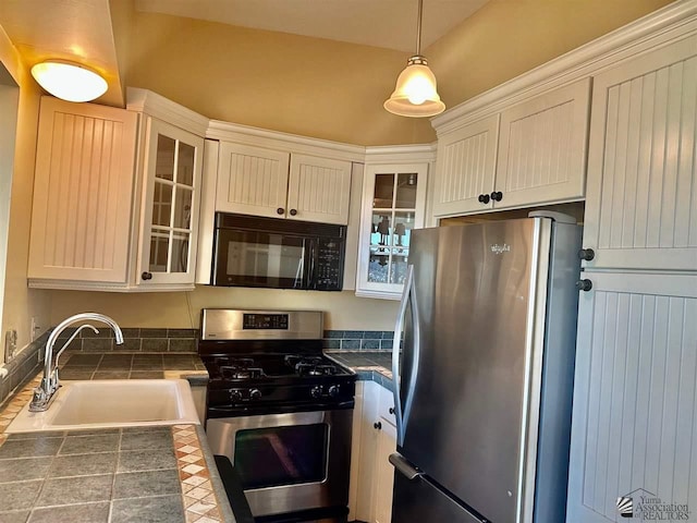 kitchen featuring sink, stainless steel appliances, white cabinets, and decorative light fixtures