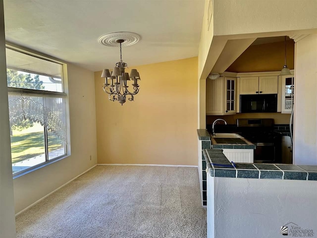 kitchen featuring an inviting chandelier, stove, a wealth of natural light, pendant lighting, and light colored carpet