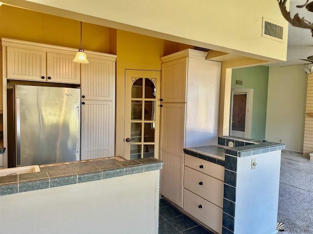 kitchen featuring dark tile patterned floors, decorative light fixtures, and stainless steel refrigerator