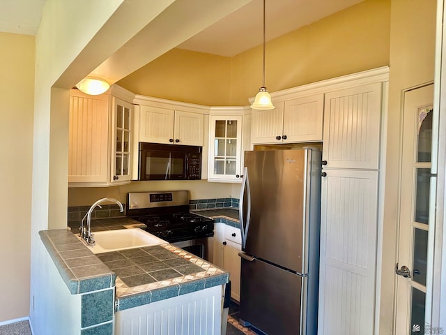 kitchen with sink, stainless steel appliances, white cabinetry, and decorative light fixtures