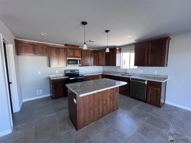 kitchen featuring sink, stainless steel appliances, light stone counters, pendant lighting, and a kitchen island