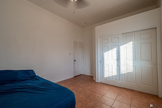 tiled bedroom with ceiling fan, a closet, and vaulted ceiling