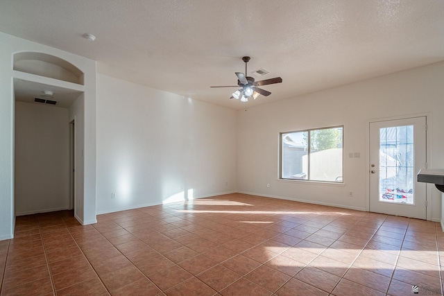 empty room featuring a textured ceiling, ceiling fan, and light tile patterned flooring