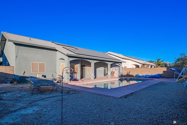 back of house with solar panels, a patio area, and a fenced in pool