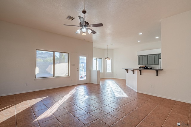 interior space featuring ceiling fan with notable chandelier and a textured ceiling