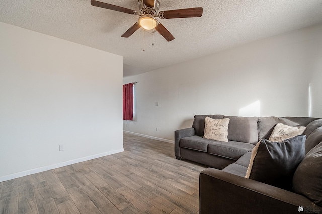 living room with ceiling fan, a textured ceiling, and light hardwood / wood-style flooring