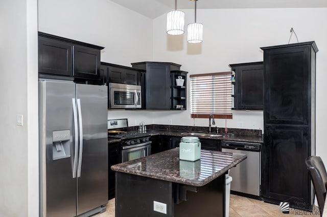 kitchen with a kitchen island, a sink, appliances with stainless steel finishes, dark cabinetry, and dark stone counters