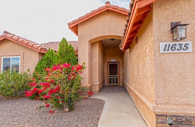 property entrance featuring a tile roof and stucco siding