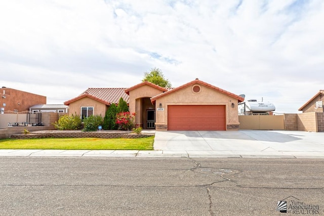 view of front of home with a garage, fence, concrete driveway, a tiled roof, and stucco siding