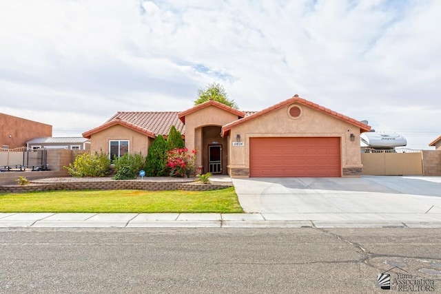 mediterranean / spanish home with a garage, fence, concrete driveway, a tiled roof, and stucco siding