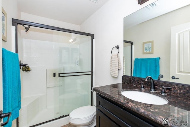 bathroom with toilet, vanity, a shower stall, and visible vents