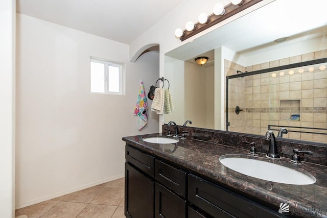 full bath featuring double vanity, a stall shower, a sink, and tile patterned floors