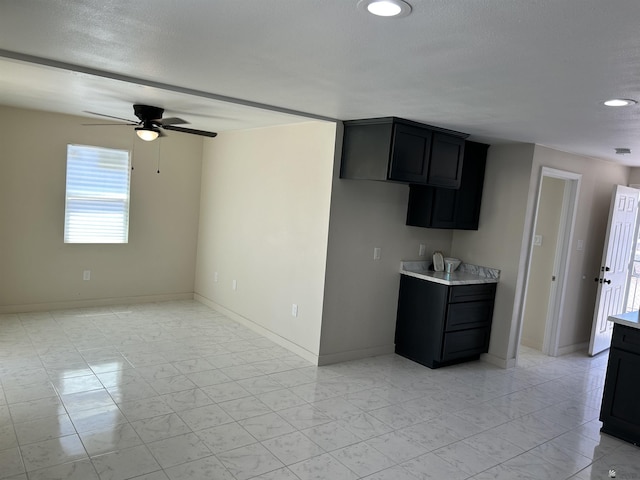kitchen featuring light countertops, ceiling fan, baseboards, and marble finish floor