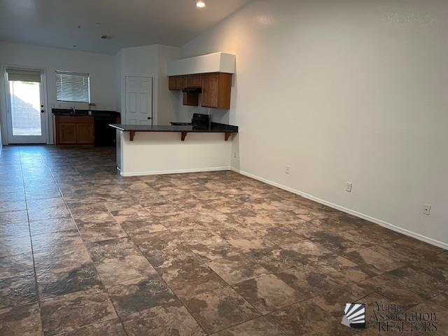 kitchen with vaulted ceiling, sink, a breakfast bar area, stove, and kitchen peninsula