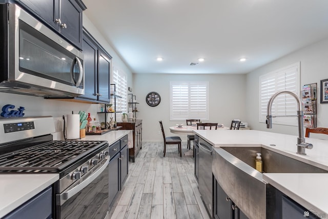 kitchen with sink, stainless steel appliances, and light wood-type flooring