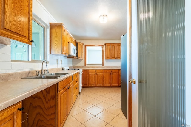 kitchen featuring white appliances, sink, and light tile patterned floors