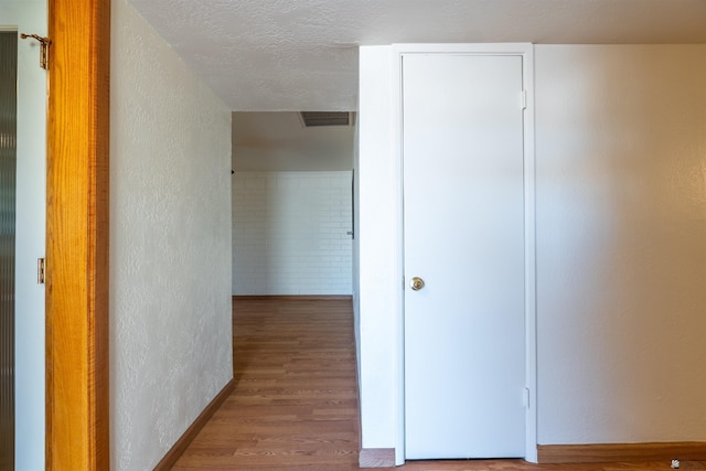 hallway featuring hardwood / wood-style floors and a textured ceiling