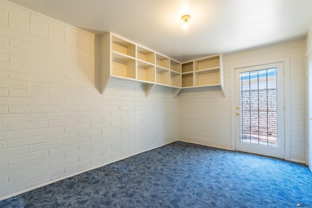 spare room with brick wall and dark carpet