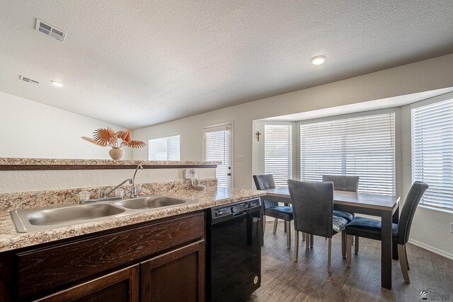 kitchen with a textured ceiling, black dishwasher, a healthy amount of sunlight, and sink