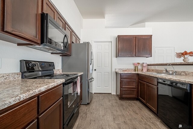 kitchen featuring dark brown cabinetry, light hardwood / wood-style flooring, black appliances, and sink