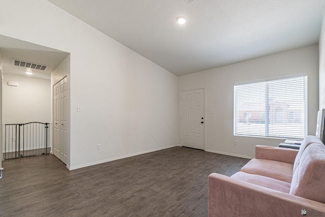 unfurnished living room featuring dark wood-type flooring and lofted ceiling