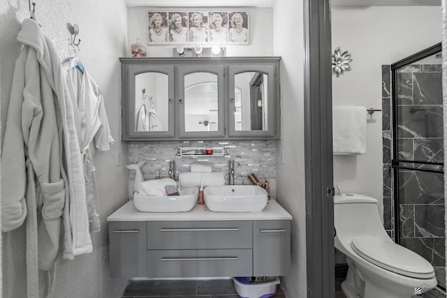 full bath with double vanity, decorative backsplash, a textured wall, toilet, and a sink