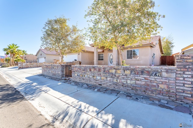 view of front of home with a fenced front yard, a tiled roof, and stucco siding