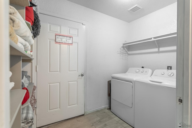 laundry area featuring laundry area, visible vents, baseboards, light wood-style flooring, and washing machine and dryer