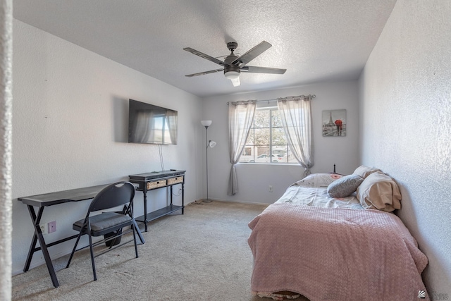 bedroom featuring baseboards, a ceiling fan, a textured wall, light colored carpet, and a textured ceiling