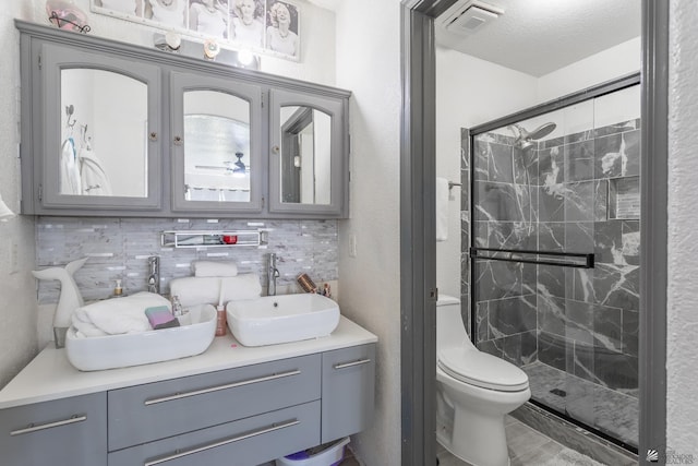 full bathroom featuring a marble finish shower, double vanity, tasteful backsplash, visible vents, and a sink