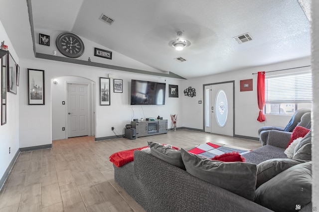 living room featuring arched walkways, vaulted ceiling, and visible vents