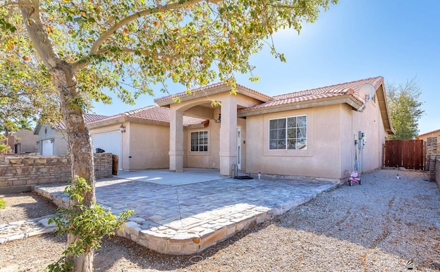 mediterranean / spanish-style home featuring an attached garage, a tiled roof, and stucco siding