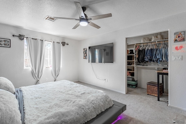 carpeted bedroom with a textured ceiling, visible vents, baseboards, a ceiling fan, and a closet