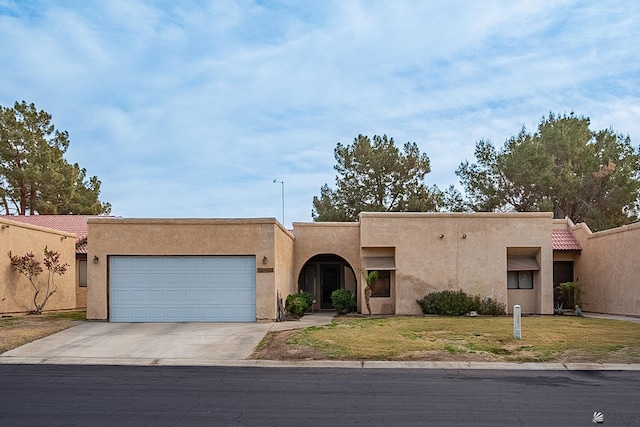 southwest-style home with stucco siding, a front lawn, driveway, a tile roof, and an attached garage